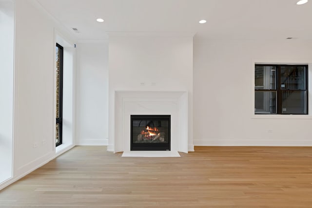 unfurnished living room with light wood-type flooring and ornamental molding