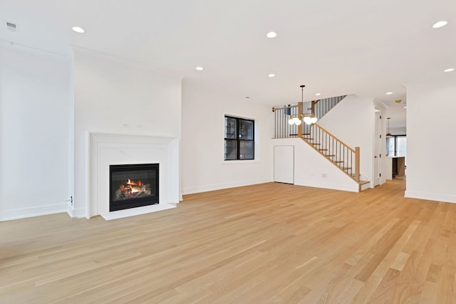 unfurnished living room featuring light wood-type flooring, an inviting chandelier, and a fireplace