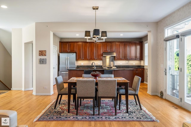 kitchen with light hardwood / wood-style flooring, stainless steel fridge, a wealth of natural light, and pendant lighting