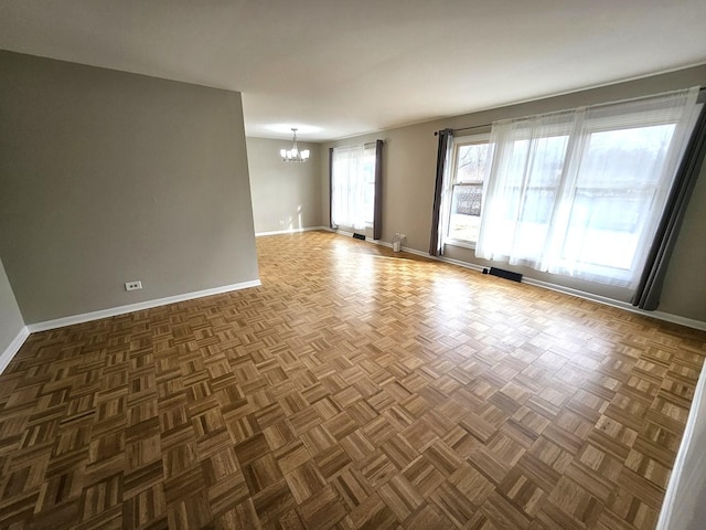 empty room with dark parquet floors and an inviting chandelier