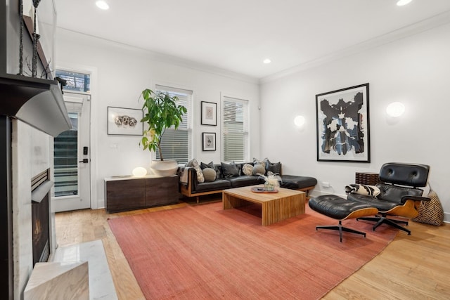 living room featuring a high end fireplace, light hardwood / wood-style flooring, crown molding, and a healthy amount of sunlight