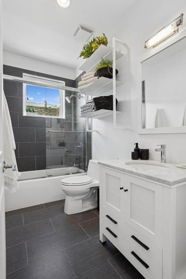 full bathroom with enclosed tub / shower combo, vanity, and toilet