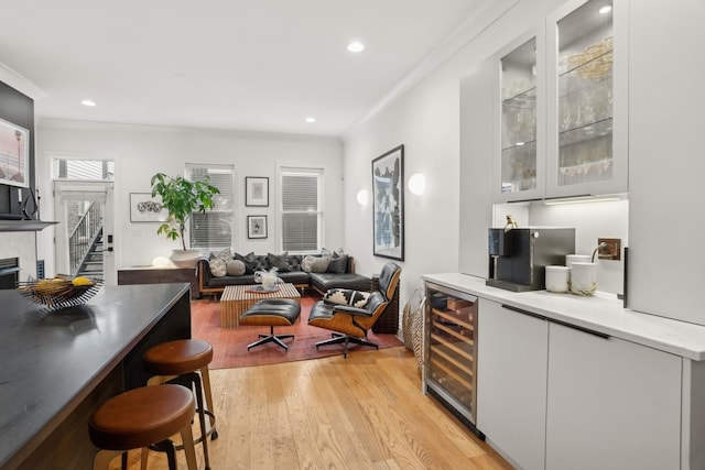 bar featuring wine cooler, a tile fireplace, ornamental molding, and light hardwood / wood-style floors