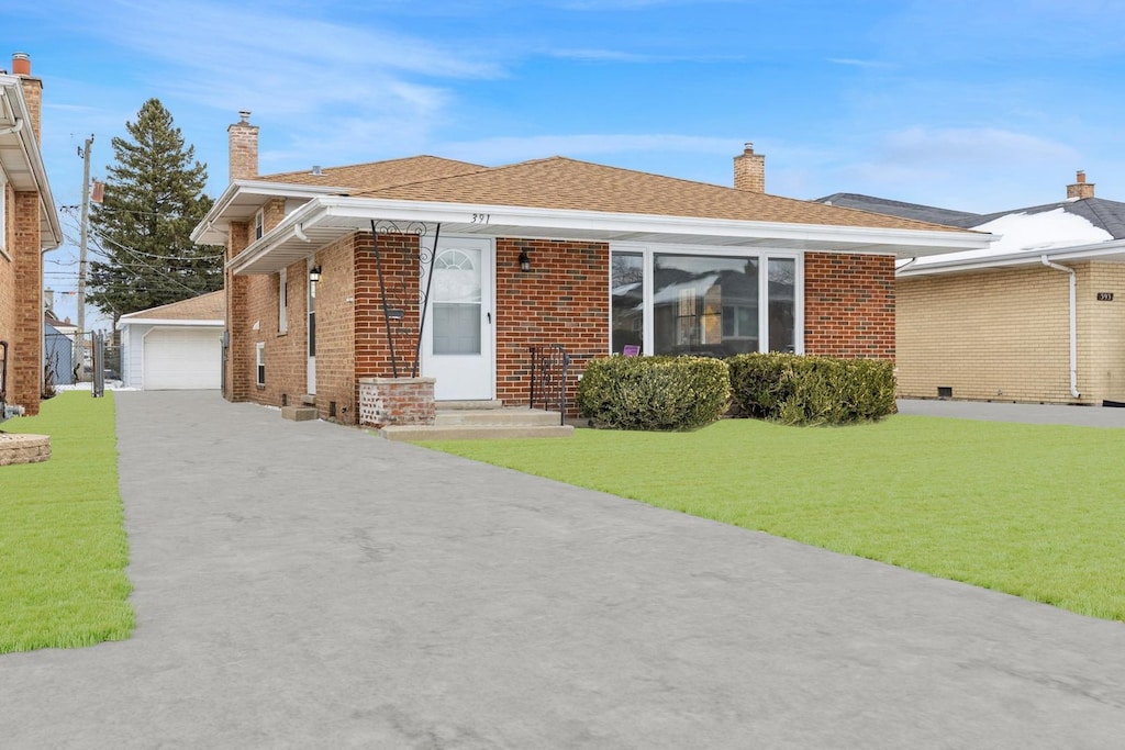 view of front of property with a garage, a front lawn, and an outdoor structure