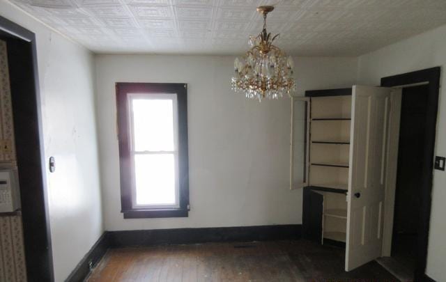 unfurnished dining area with a chandelier and dark hardwood / wood-style floors