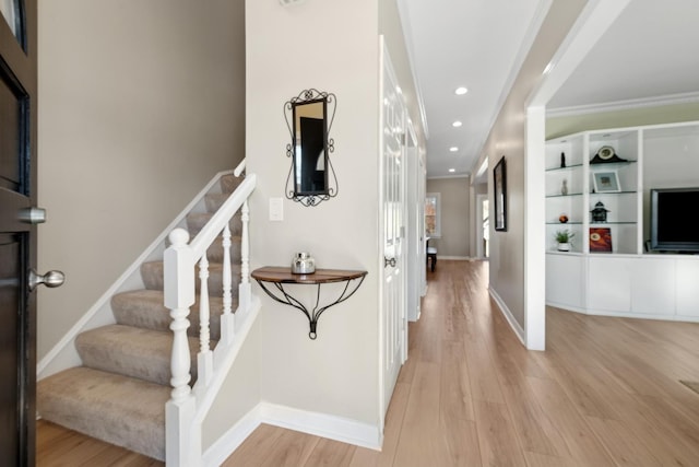 stairs with ornamental molding and wood-type flooring