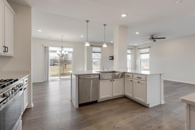 kitchen featuring sink, range with gas cooktop, white cabinetry, dishwasher, and pendant lighting