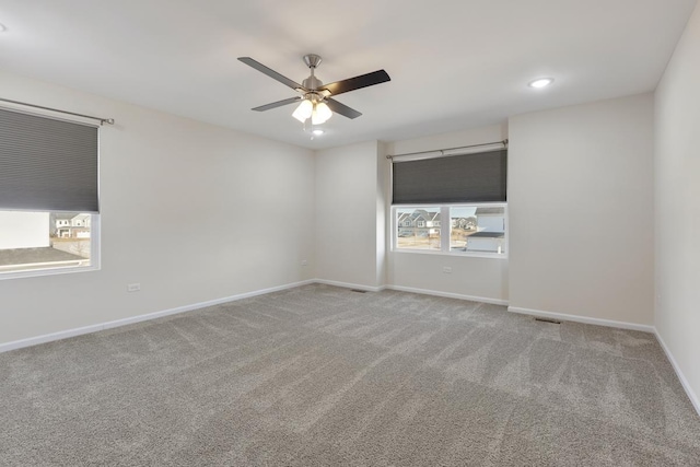 carpeted empty room with ceiling fan and plenty of natural light