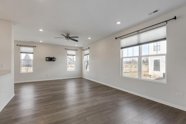 empty room with dark wood-type flooring, a barn door, and ceiling fan