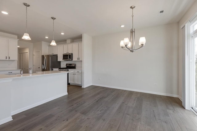 kitchen featuring appliances with stainless steel finishes, hanging light fixtures, and white cabinets