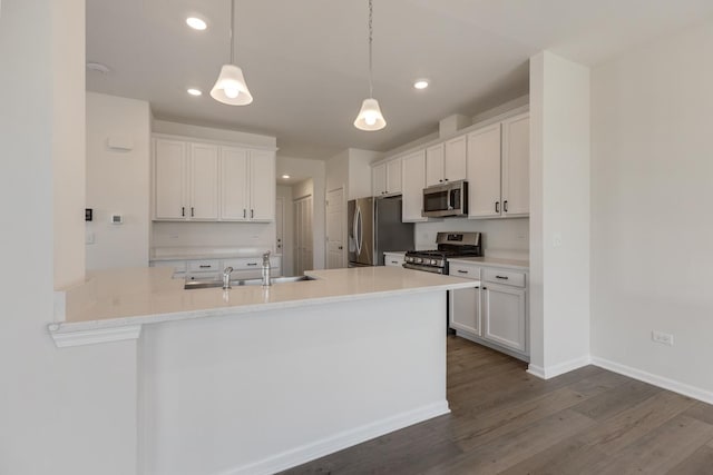 kitchen with hardwood / wood-style flooring, white cabinetry, hanging light fixtures, stainless steel appliances, and kitchen peninsula