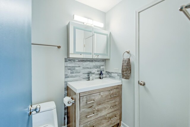 bathroom featuring toilet, backsplash, and vanity