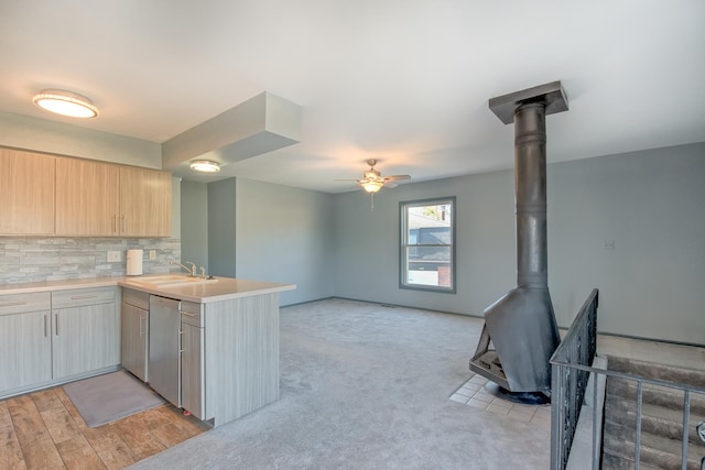 kitchen featuring dishwasher, light brown cabinetry, a wood stove, kitchen peninsula, and ceiling fan