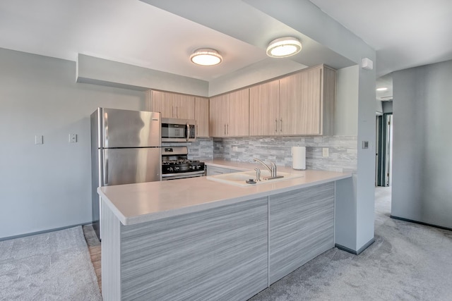 kitchen with tasteful backsplash, kitchen peninsula, sink, stainless steel appliances, and light brown cabinetry