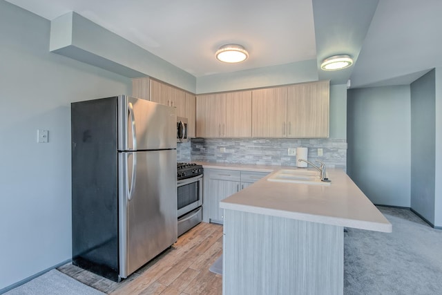 kitchen featuring appliances with stainless steel finishes, light brown cabinetry, sink, backsplash, and kitchen peninsula