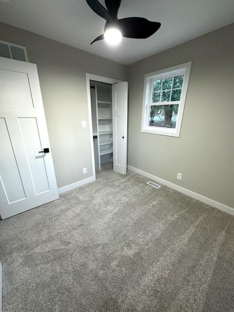 unfurnished bedroom with ceiling fan, a closet, and carpet floors