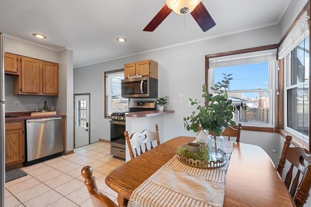 dining space with ceiling fan, light tile patterned floors, and ornamental molding