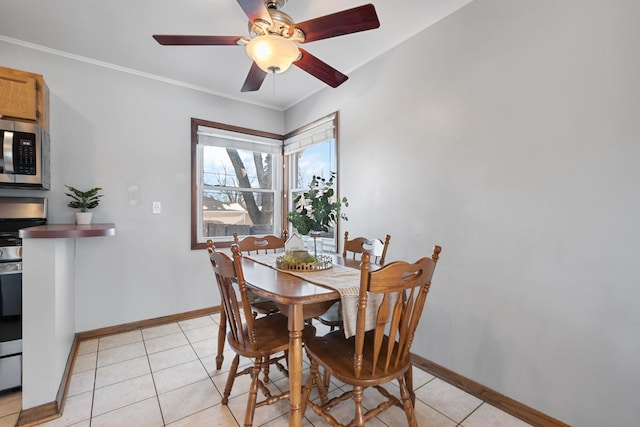 tiled dining area with ceiling fan and crown molding