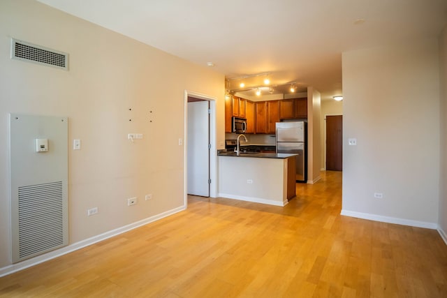 kitchen with kitchen peninsula, sink, light hardwood / wood-style flooring, appliances with stainless steel finishes, and track lighting