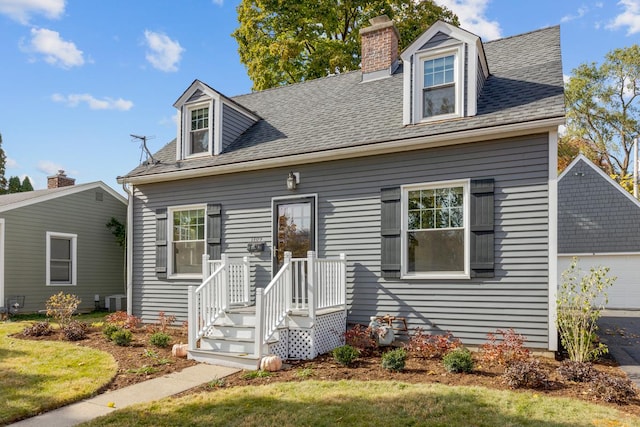 cape cod home featuring central AC unit and a front lawn