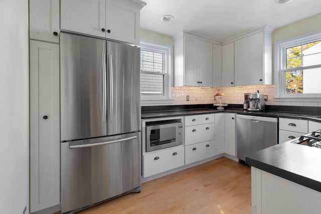 kitchen featuring appliances with stainless steel finishes, a healthy amount of sunlight, light hardwood / wood-style floors, and white cabinetry