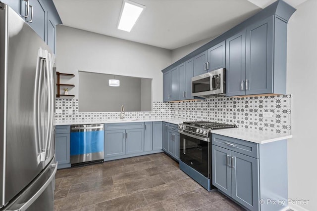 kitchen featuring pendant lighting, sink, stainless steel appliances, blue cabinets, and decorative backsplash