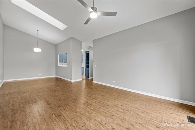 unfurnished living room featuring high vaulted ceiling, hardwood / wood-style floors, ceiling fan, and a skylight