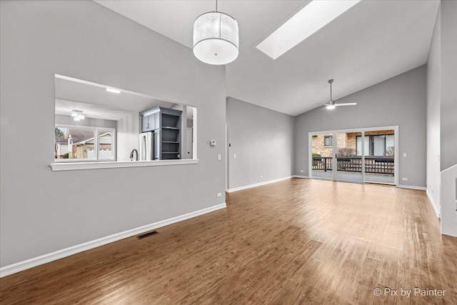 unfurnished living room featuring hardwood / wood-style floors, a skylight, ceiling fan, and plenty of natural light