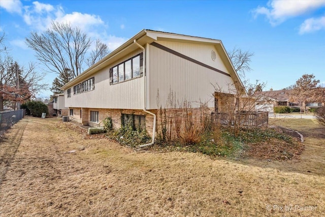 view of side of property with a yard and central AC