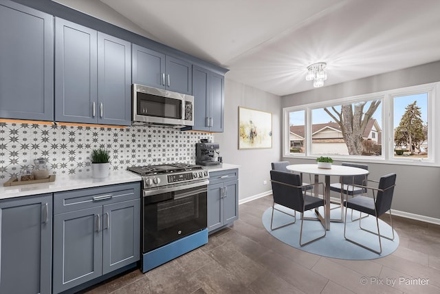 kitchen with vaulted ceiling, appliances with stainless steel finishes, dark hardwood / wood-style floors, and decorative backsplash