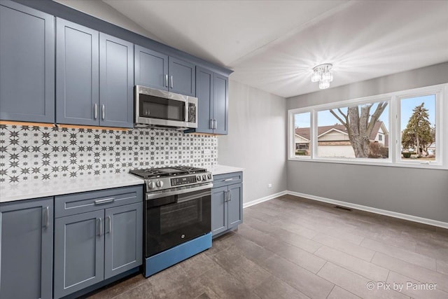 kitchen featuring dark wood-type flooring, lofted ceiling, stainless steel appliances, and decorative backsplash