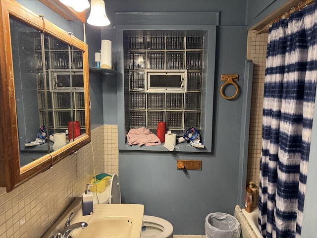 bathroom with toilet, a shower with curtain, tasteful backsplash, and sink