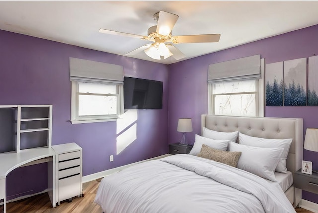 bedroom featuring ceiling fan, multiple windows, and light hardwood / wood-style flooring