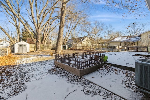 yard layered in snow with central AC unit and a shed