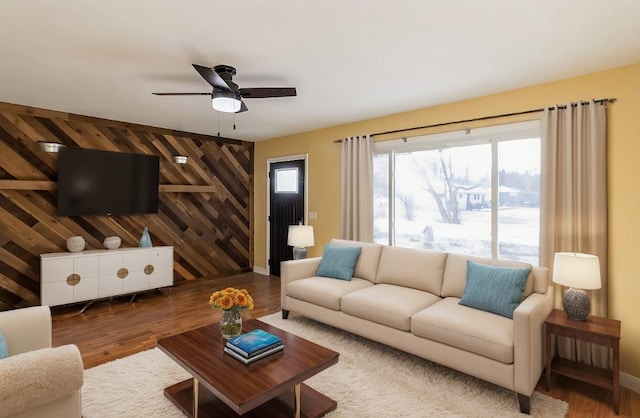 living room with ceiling fan, wooden walls, and hardwood / wood-style flooring