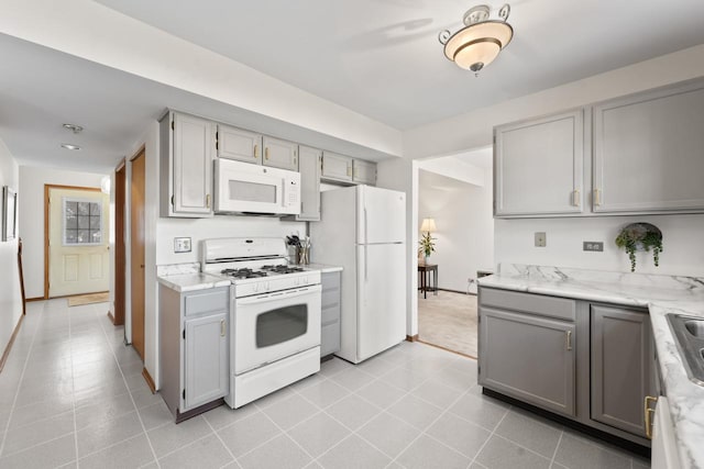 kitchen with white appliances, baseboards, gray cabinetry, and light stone countertops