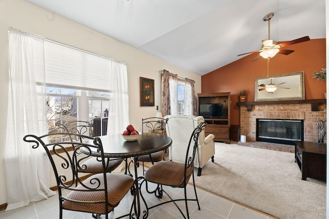 dining area featuring a ceiling fan, lofted ceiling, a brick fireplace, and carpet