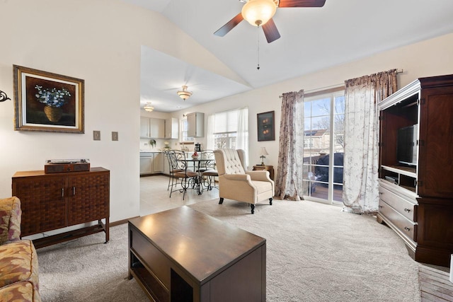 living room featuring lofted ceiling, a ceiling fan, and light colored carpet