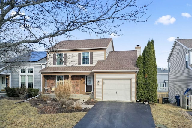 traditional-style home featuring an attached garage, covered porch, brick siding, driveway, and a chimney