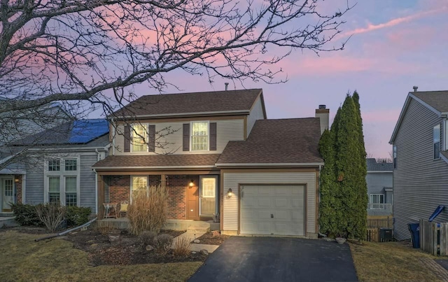 traditional-style home with a chimney, covered porch, central AC, a garage, and driveway