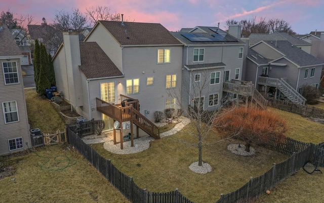 back of property featuring a chimney, a lawn, stairway, a deck, and a fenced backyard