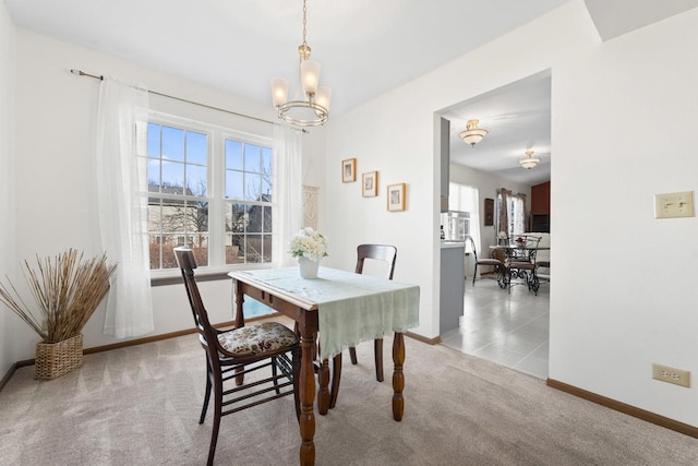 carpeted dining space with a notable chandelier and baseboards