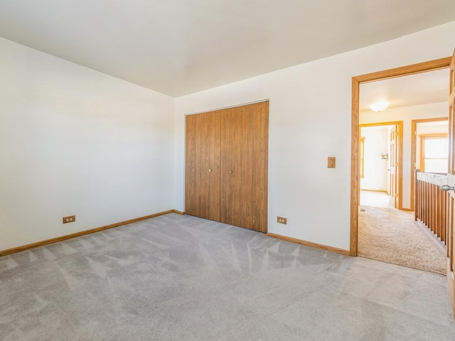 unfurnished bedroom with light colored carpet and a closet