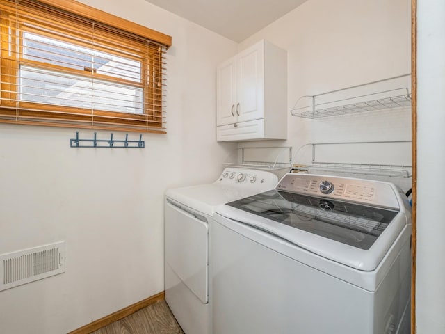 laundry area with hardwood / wood-style floors, cabinets, and washer and dryer