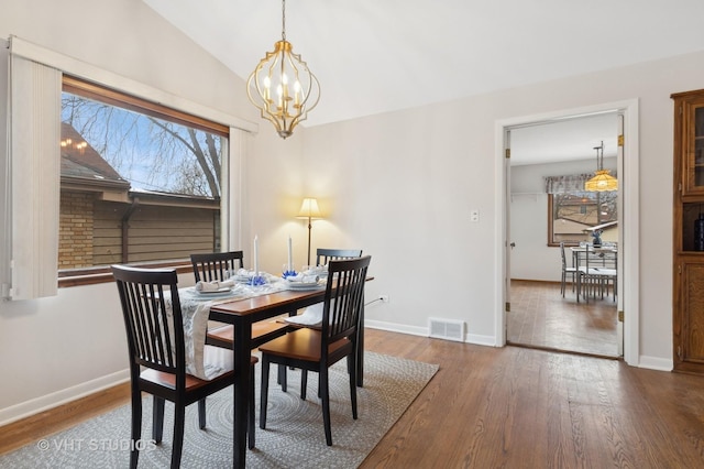 dining area with dark hardwood / wood-style flooring, a notable chandelier, and lofted ceiling