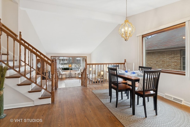 dining area featuring a notable chandelier, hardwood / wood-style flooring, and vaulted ceiling with beams