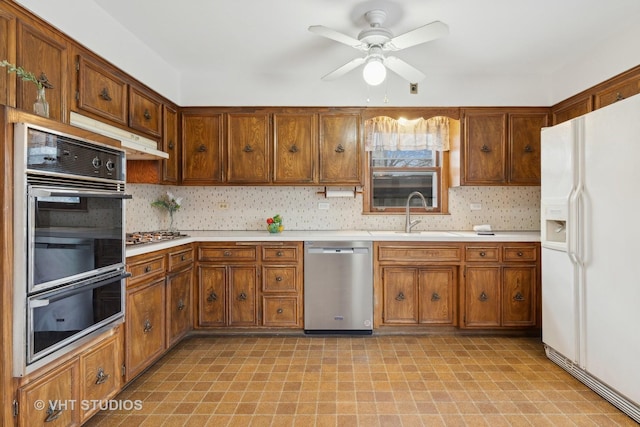 kitchen featuring appliances with stainless steel finishes, sink, backsplash, and ceiling fan