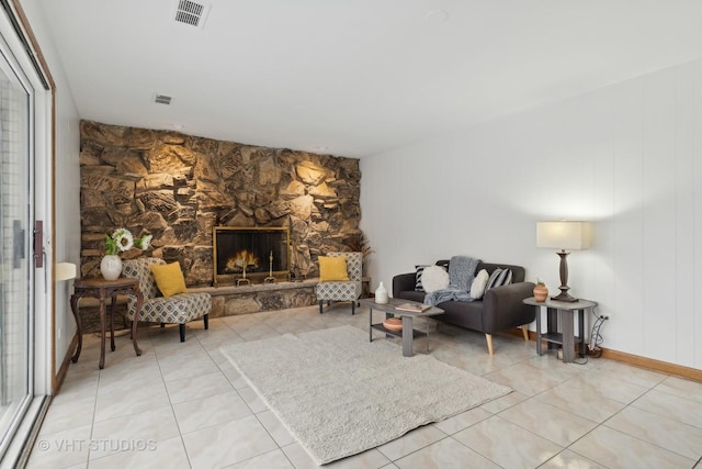 living room with a stone fireplace and light tile patterned floors