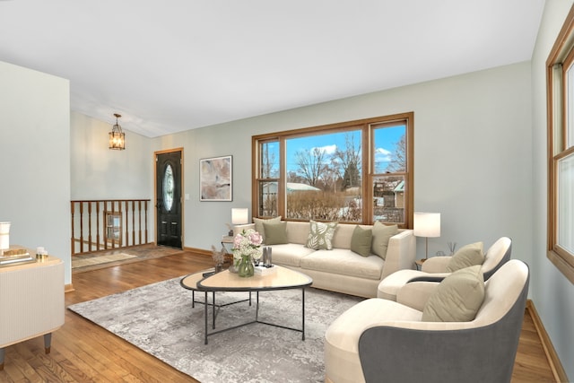 living room featuring wood-type flooring, a notable chandelier, and vaulted ceiling