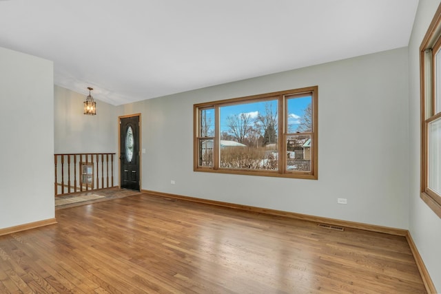 unfurnished room with vaulted ceiling, an inviting chandelier, and light hardwood / wood-style floors